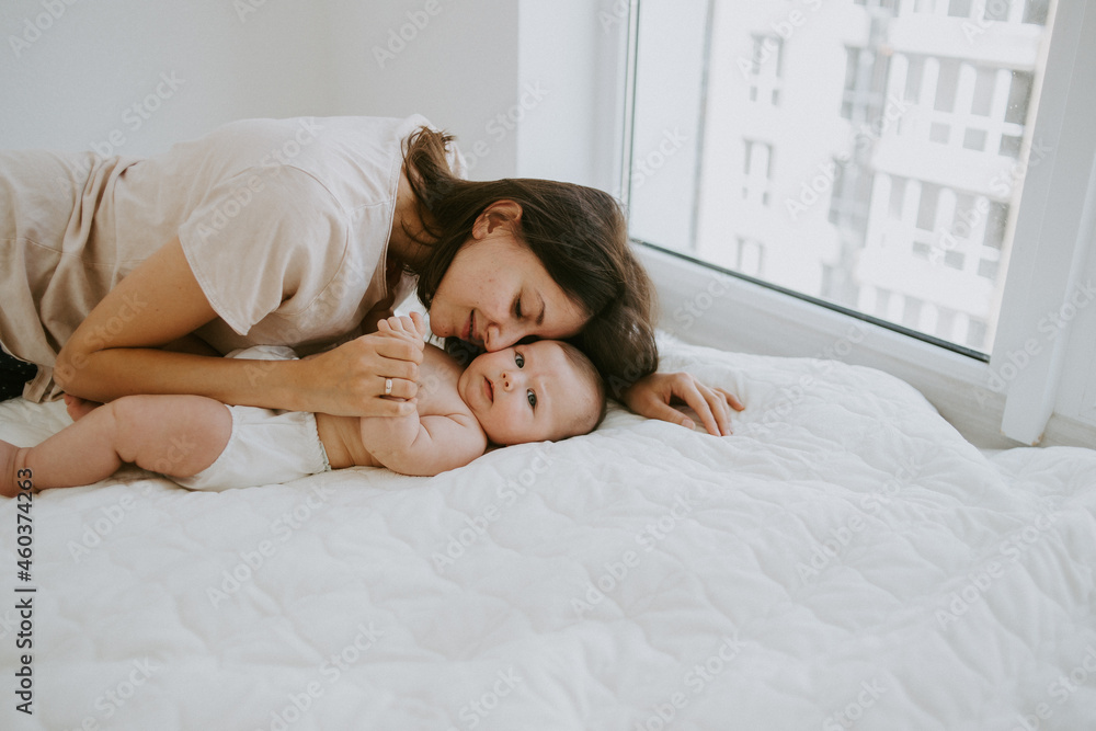 Love of a mother and baby. Family in the house. Lifestyle Home portrait of newborn baby with mother on bed. Mom holds and kisses her baby.
Love of a mother and baby. Family in the house. Lifestyle Home portrait of newborn baby with mother on bed. Mom holds and kisses her baby.