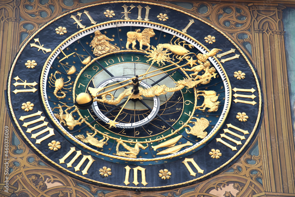 antique city hall clock on painted wall of city hall, golden arrow and dragon as clock hands on blue clock face, golden Roman numerals on outer ring and golden zodiac signs in inner ring