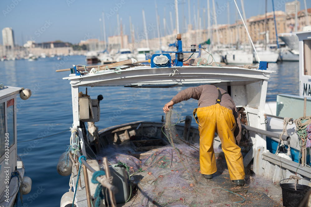 Le pêcheur sur le bateau de pêche lié par le marché au poisson de ...