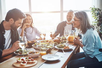 Happy multi-generation family communicating and smiling while having dinner together