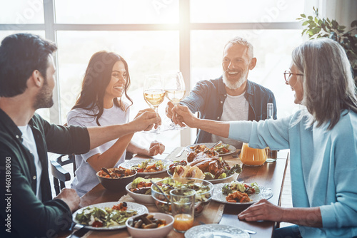 Happy multi-generation family toasting each other and smiling while having dinner together