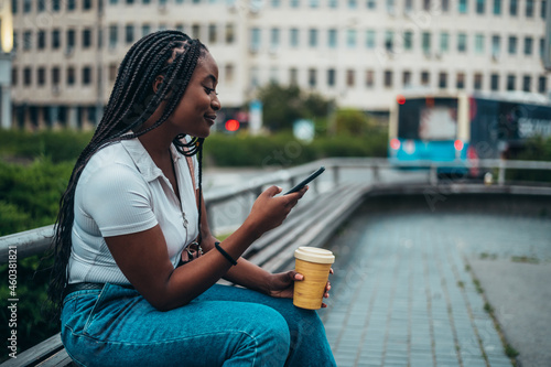Beautiful african american woman using smartphone and drinking coffee takeaway © Zamrznuti tonovi