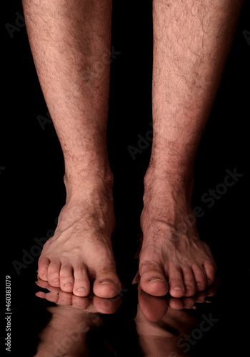 Barefoot man standing on reflective surface