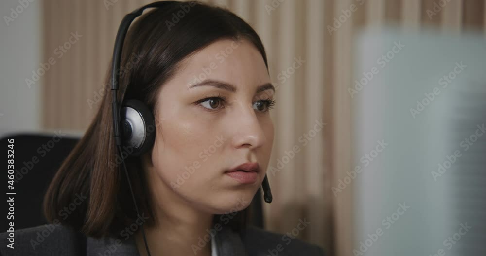 Contact center worker - a young girl in headphones communicates with a client Contact center worker - a young girl in headphones communicates with a client