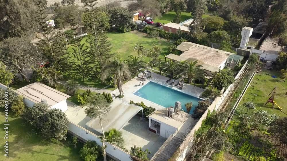 Aerial drone view of several country houses with swimming pools on a sunny day with trees and green vegetation and friends enjoying the day near the water Aerial drone view of several country houses with swimming pools on a sunny day with trees and green vegetation and friends enjoying the day near the water