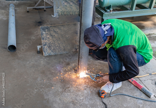 A welder welds a metal pole without gloves and mask.