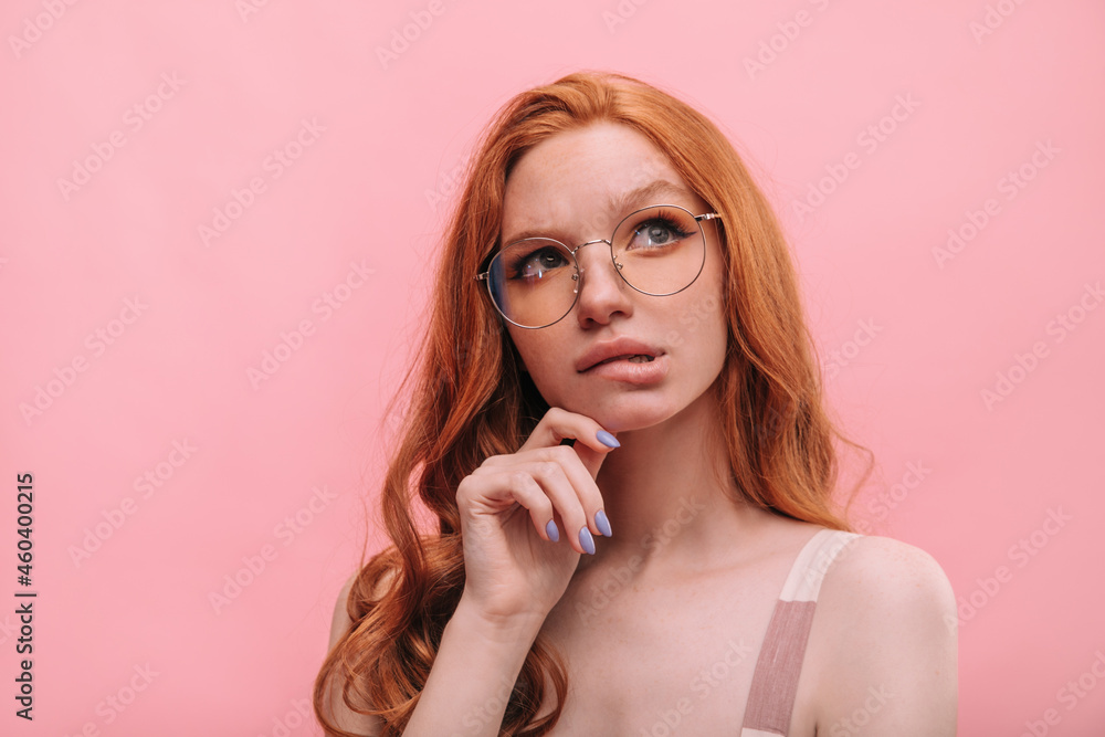 Close-up of fair-skinned young woman wearing glasses biting her lower lip looking up. Red-haired long-haired beauty with full lips in thinking about something. Waiting, loneliness and beauty concept Close-up of fair-skinned young woman wearing glasses biting her lower lip looking up. Red-haired long-haired beauty with full lips in thinking about something. Waiting, loneliness and beauty concept
