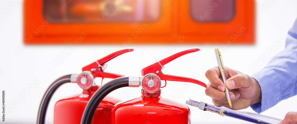 Naklejka premium Fire extinguisher, Engineer inspection checking pressure gauge level fire extinguisher tank with fire hose cabinet of protection and prevent emergency and safety rescue and fire alarm system training.