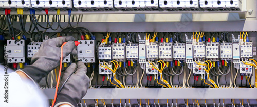 Electricity and electrical maintenance service, Close-up circuit breaker has engineer using measuring equipment checking electric volt at terminal block and cable wiring main power distribution board.