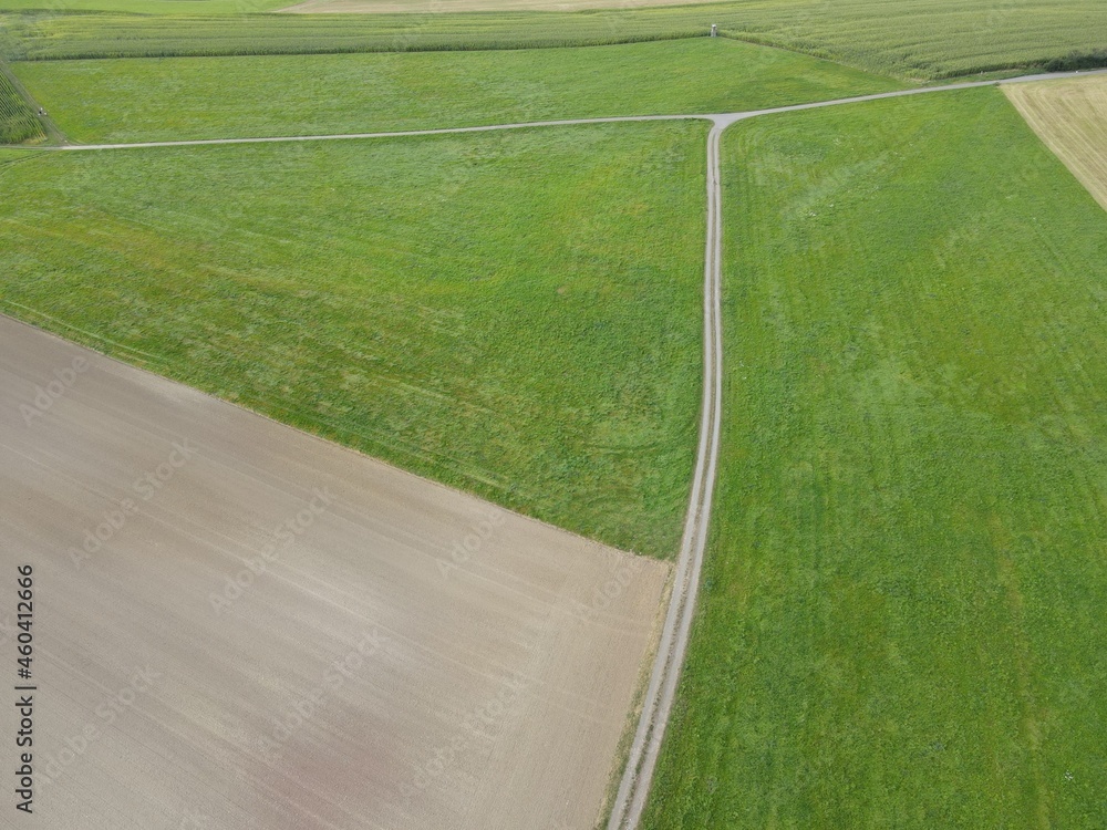 Aerial view of tractor track made of gravel between fields in summer