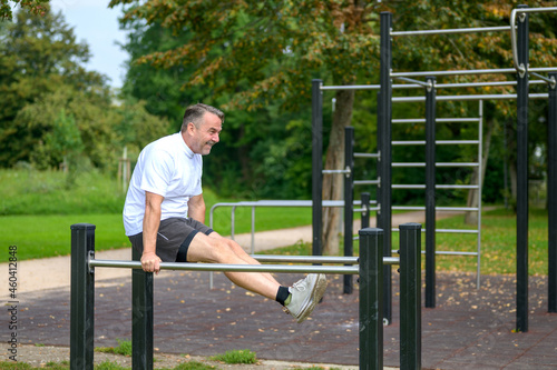 Senior man working out on outdoor parallel bars
