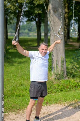 Senior man using rings at an outdoor sports facility