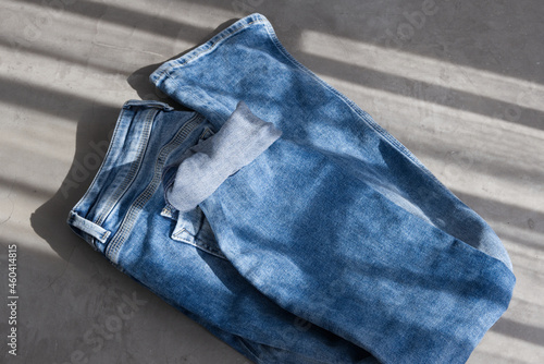 a blue light folded jeans on a grey background. Sunlight (ID: 460414815)