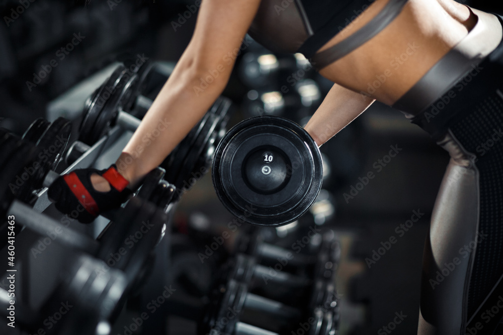 Slim, bodybuilder girl, lifts heavy dumbbell standing in front of the mirror while training in the gym. Sports concept, fat burning and a healthy lifestyle. Slim, bodybuilder girl, lifts heavy dumbbell standing in front of the mirror while training in the gym. Sports concept, fat burning and a healthy lifestyle.