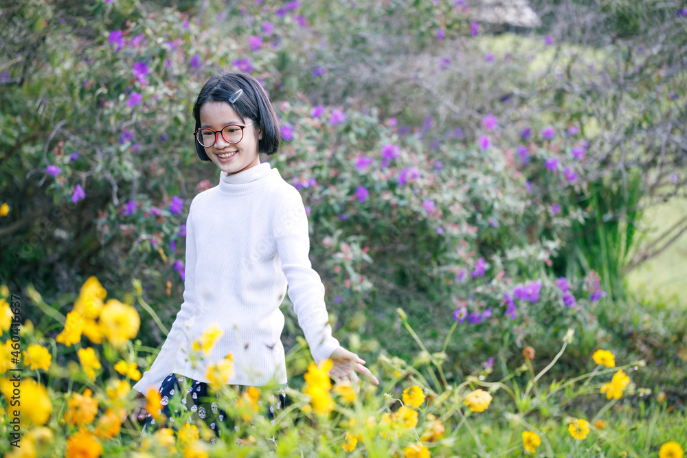Happy smile Asian teen girl with glasses walks in the autumn flowers park Happy smile Asian teen girl with glasses walks in the autumn flowers park