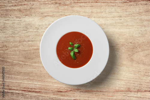 Tomato soup in white plate on wooden background