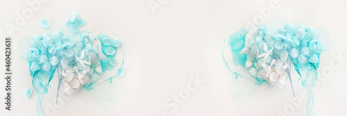 Creative image of pastel blue and pink Hydrangea flowers on artistic ink background. Top view with copy space