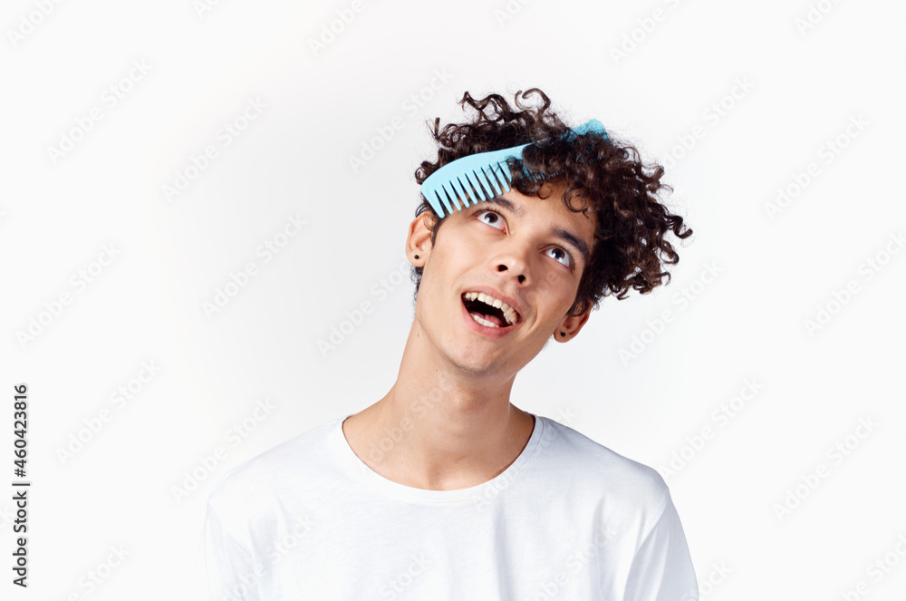 a guy in a white t-shirt combs curly hair a guy in a white t-shirt combs curly hair