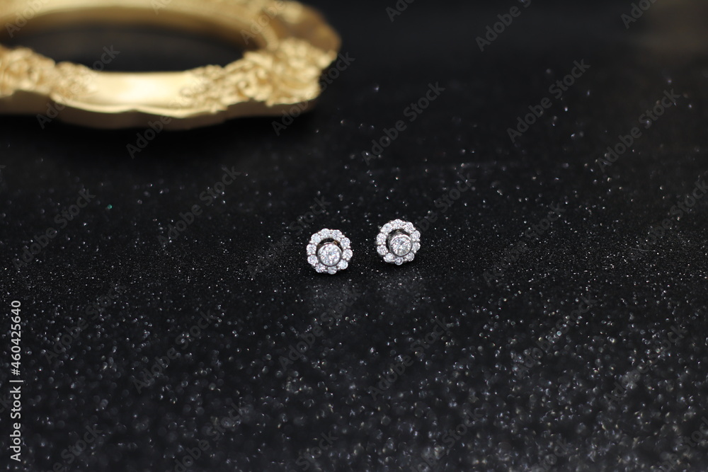 Diamonds with white gold earring setting on black satin fabric. Fine Jewelry photo set for engagement or wedding ceremony Diamonds with white gold earring setting on black satin fabric. Fine Jewelry photo set for engagement or wedding ceremony
