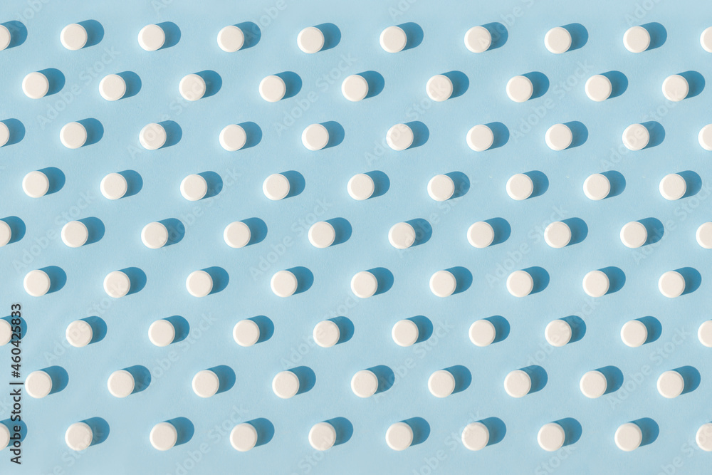 Pattern made with Pharmaceutical medicine tablets on bright light blue background. Medicine creative concepts.