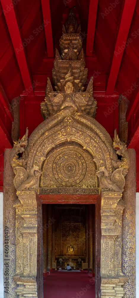 View of beautiful gilded stucco framing the entrance of ancient Viharn Lai Kham at landmark Wat Phra Singh buddhist temple, Chiang Mai, Thailand
