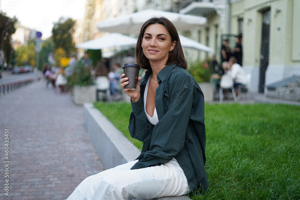 Woman with cup of coffee outdoor at city street at sunset happy smiling enjoying summer days