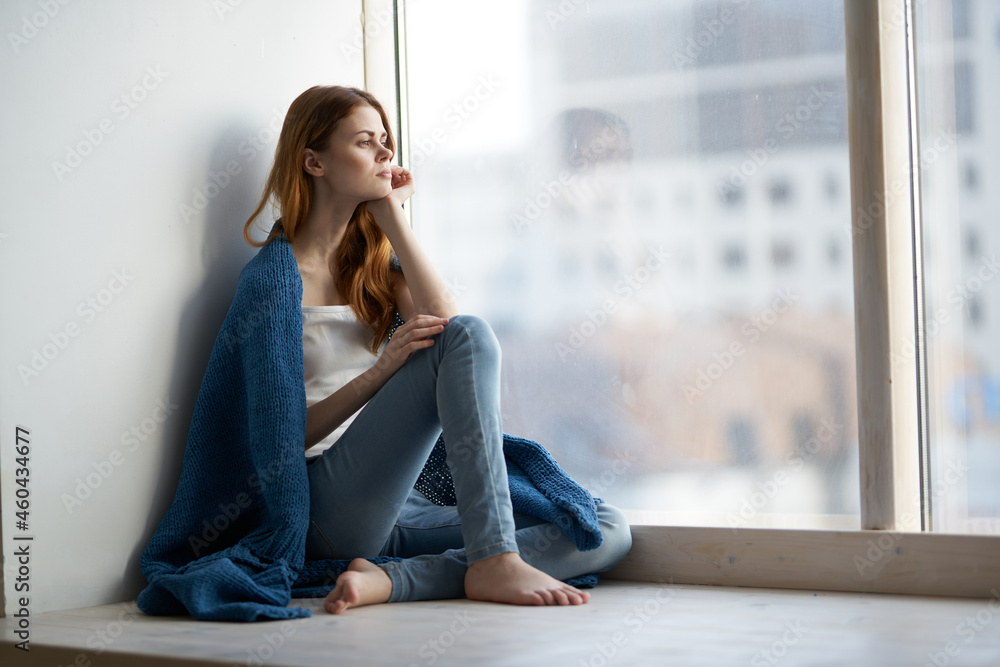 woman sitting near the window with a blue plaid smile at home woman sitting near the window with a blue plaid smile at home