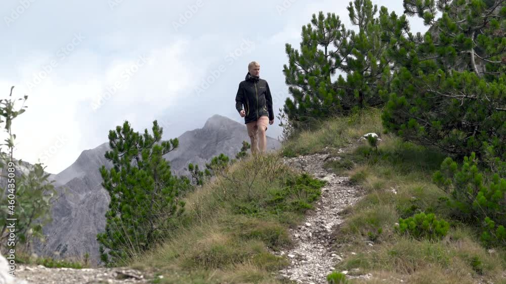 Young man hiker tourist descends from the mountain hill by the stony path. Young man hiker tourist descends from the mountain hill by the stony path.
