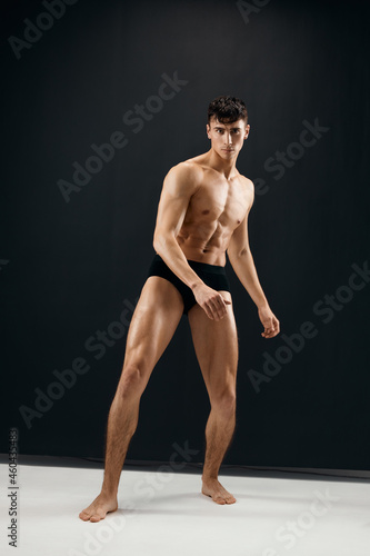 man in black shorts with a muscular body on a dark background