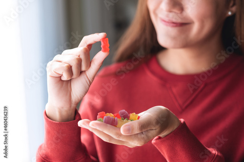 Closeup image of a young woman holding and looking at a red jelly gummy bear photo
