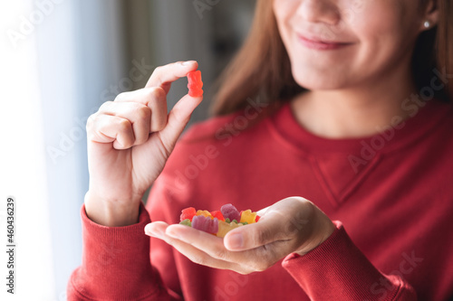 Vászonkép Closeup image of a young woman holding and looking at a red jelly gummy bear