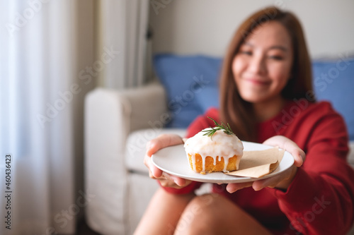 A young woman holding and eating a piece of lemon pound cake at home