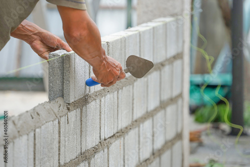 Schilderij op canvas bricklayer hands hold  aluminium brick trowel installing brick blocks on constru