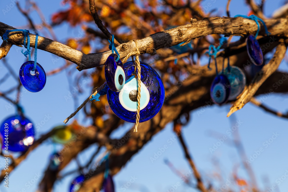 Blue evil eye / nazar boncugu, Turkish symbols hanging on a tree; Cappadocia Blue evil eye / nazar boncugu, Turkish symbols hanging on a tree; Cappadocia