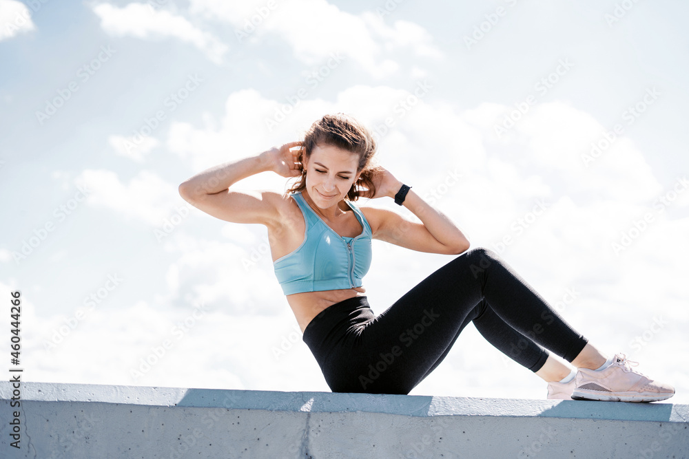 Fototapeta premium The trainer does warm-up exercises before training. The athlete leads a healthy lifestyle. Cardio training for weight loss. Sports and clothing for women. Fitness in the city.