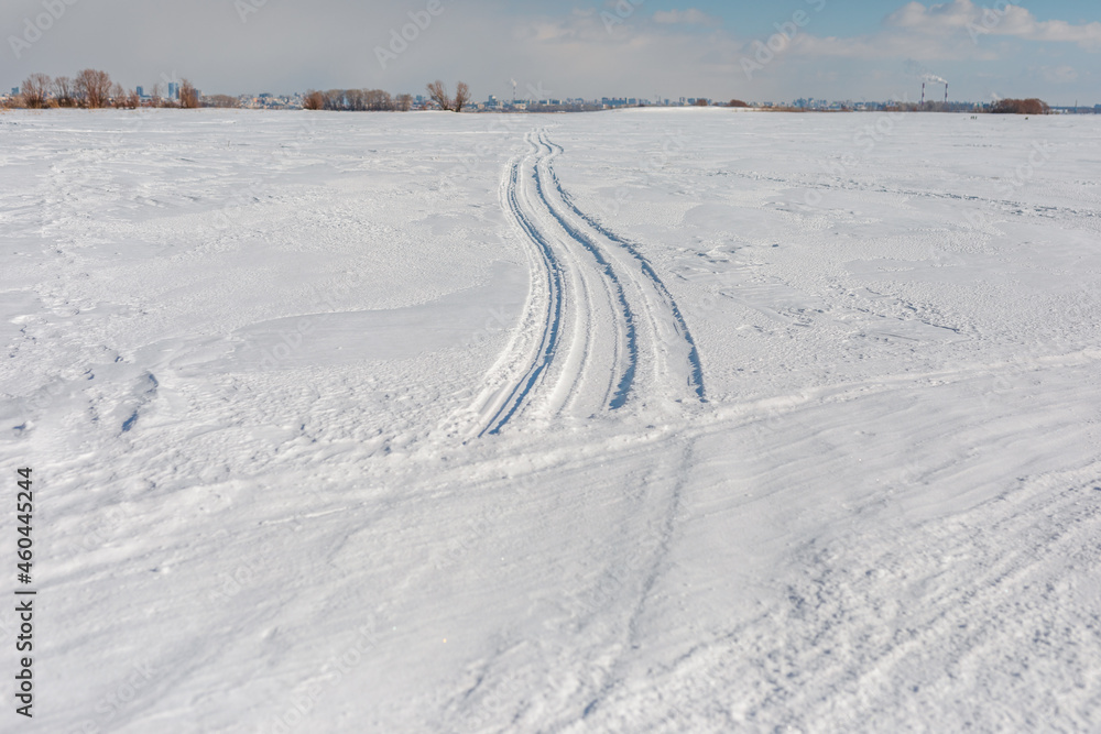 Car tracks in the snow go into the distance. Wheel tracks on a snow road.