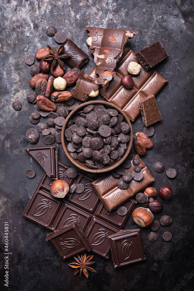 Chocolate background with lots of bars, nuts, drops and cocoa beans Chocolate background with lots of bars, nuts, drops and cocoa beans