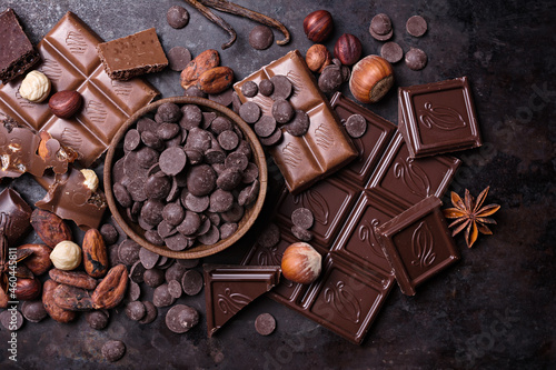 Chocolate background with lots of bars, nuts, drops and cocoa beans