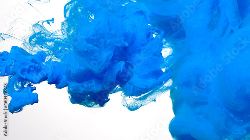 Colored acrylic paints in water. Blue watercolor ink in water on a white background. Blue cloud of ink on a white background. Abstract background.
