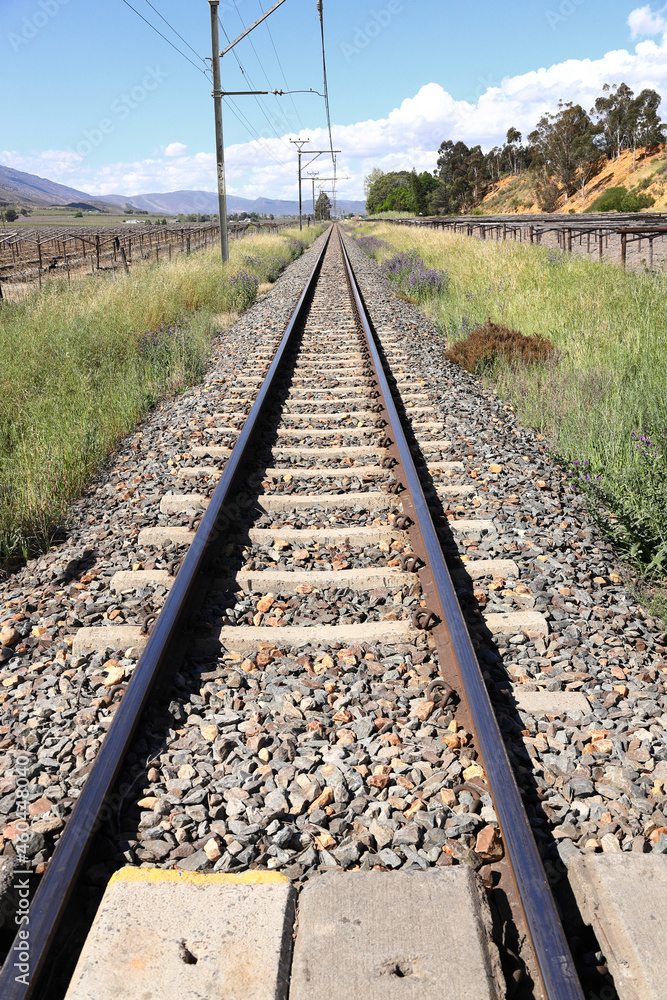A photo of railway lines in a rural setting in bright sunshine.  It runs through the farming community of De Doorns in the Western Cape Province in South Africa.