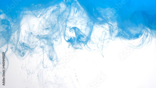 Blue watercolor ink in water on a white background. Beautiful abstract background. Blue paints are mixed in water.