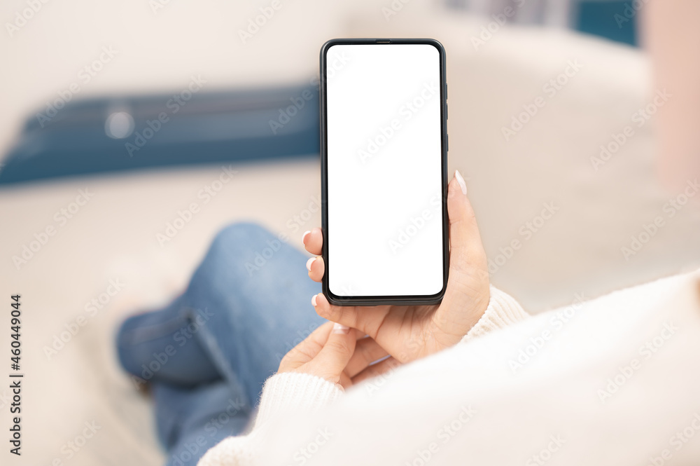 working at home using with smart cell phone. Woman using smartphone frameless mockup blank screen in home interior. Unrecognizable woman hold cellphone with empty screen at home working at home using with smart cell phone. Woman using smartphone frameless mockup blank screen in home interior. Unrecognizable woman hold cellphone with empty screen at home