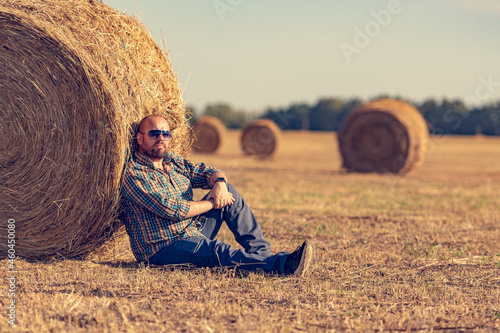 Bilde på lerret A golden bale of hay, leaning on which a man is resting