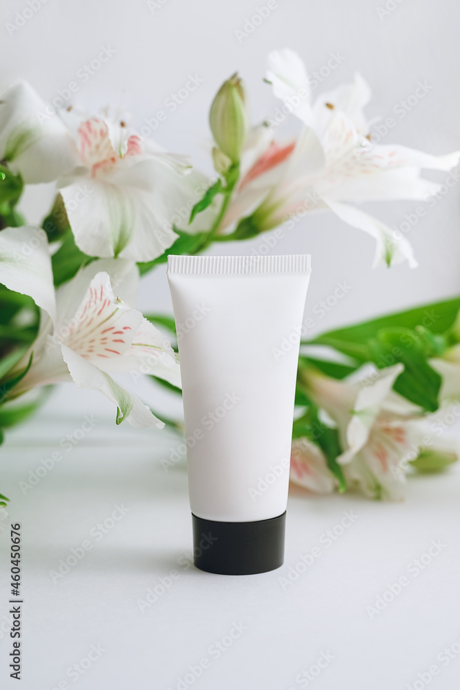 tube of moisturizer and alstroemeria on a white background close-up tube of moisturizer and alstroemeria on a white background close-up