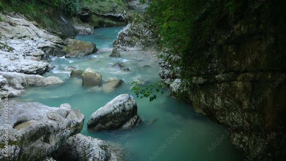 Wild Mountain River Flowing with Stone Boulders and Stone Rapids. Rapid Splashing water in Creek. Mountain stream in the Winter. Abundant Clear Stream. Okatsi Gorge Wild Mountain River Flowing with Stone Boulders and Stone Rapids. Rapid Splashing water in Creek. Mountain stream in the Winter. Abundant Clear Stream. Okatsi Gorge