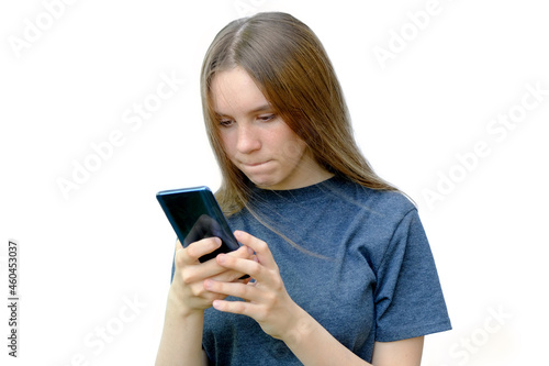 Girl teenager looks at the phone. The girl with pursed lips, agitated upset. Isolated on white. Horizontal photo.