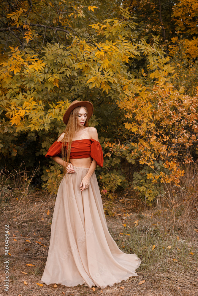 an attractive woman in a brown hat in the fall on a deciduous background. autumn trend