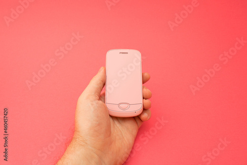 Hand holding pink 3d smartphone against red background. 3D illustration design template background. Top mobile phone message. Advertisement idea. Empty copy space for ad