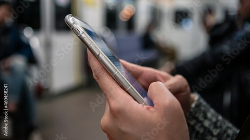 Asian young woman checks her phone, and writting SMS text inside japanese metro