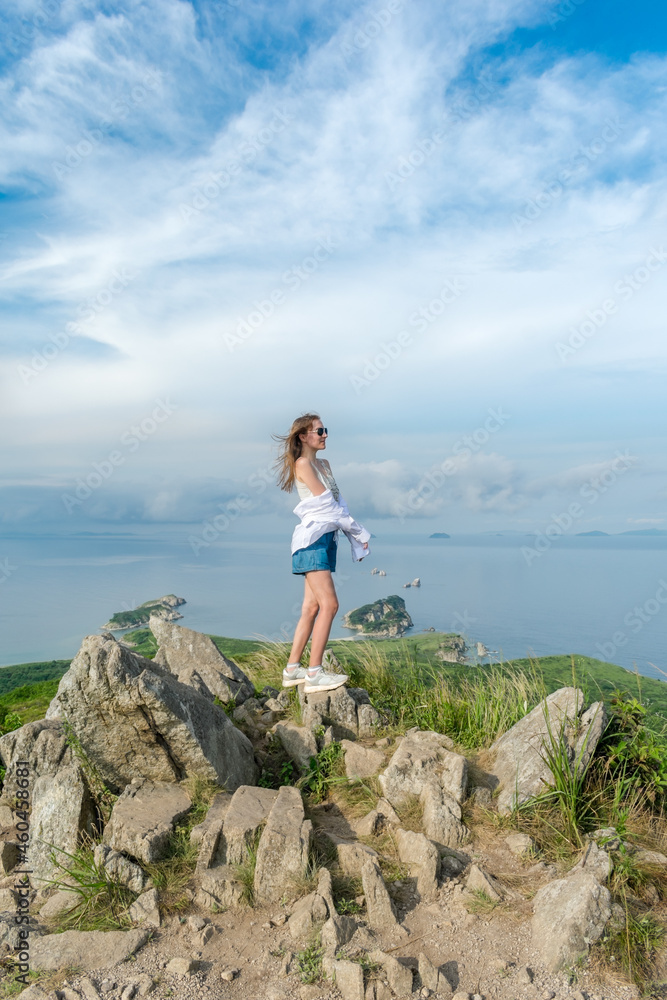Girl in summer clothes on the top of the mountain near the sea